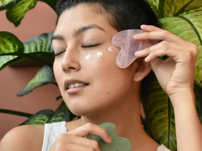 A woman sweeping a gua sha stone across her cheek
